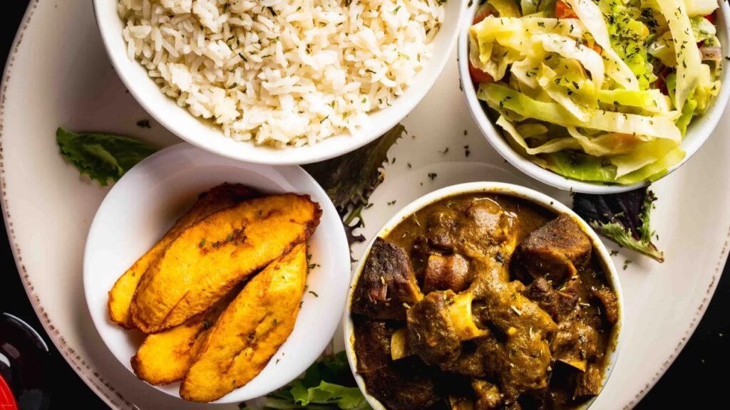 Curry goat with white rice, sweet plantains and cabbage