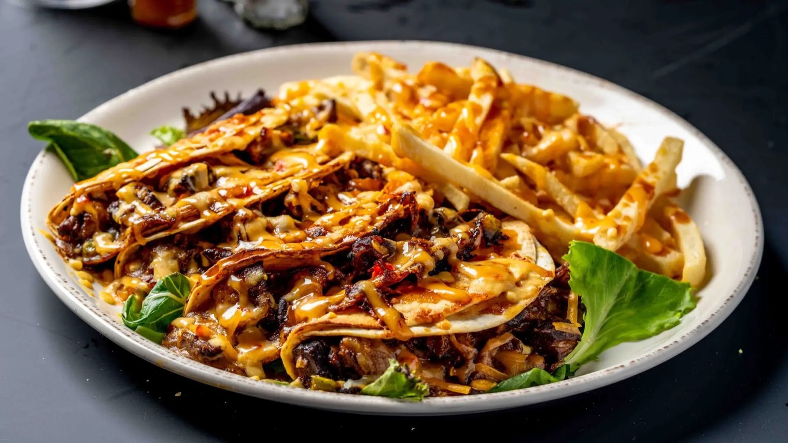 Folded tortillas filled with shredded meat and cheese sauce, served with fries
