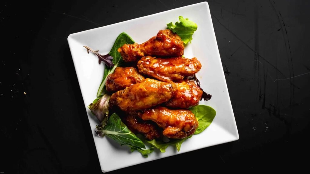 Glazed chicken wings on a bed of greens